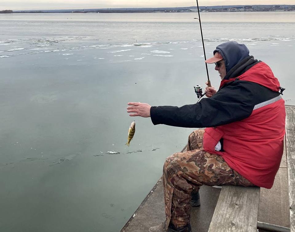 Steve Maenpaa, a 59-year-old man from Conneaut, Ohio, hauls in a perch while fishing Feb. 8 at Presque Isle State Park's Waterworks Ferry Dock. Warm weather has allowed people to fish along the peninsula's shoreline most of the winter.