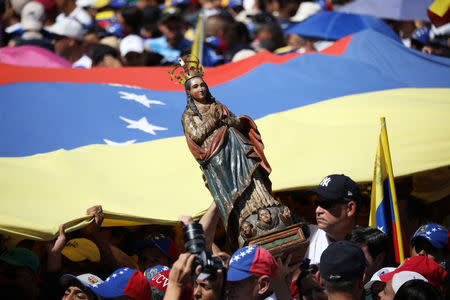 Opposition supporters hold Venezuelan flag and a Virgin Mary figure as they take part in a rally against Venezuelan President Nicolas Maduro's government in Caracas, Venezuela February 2, 2019. REUTERS/Andres Martinez Casares