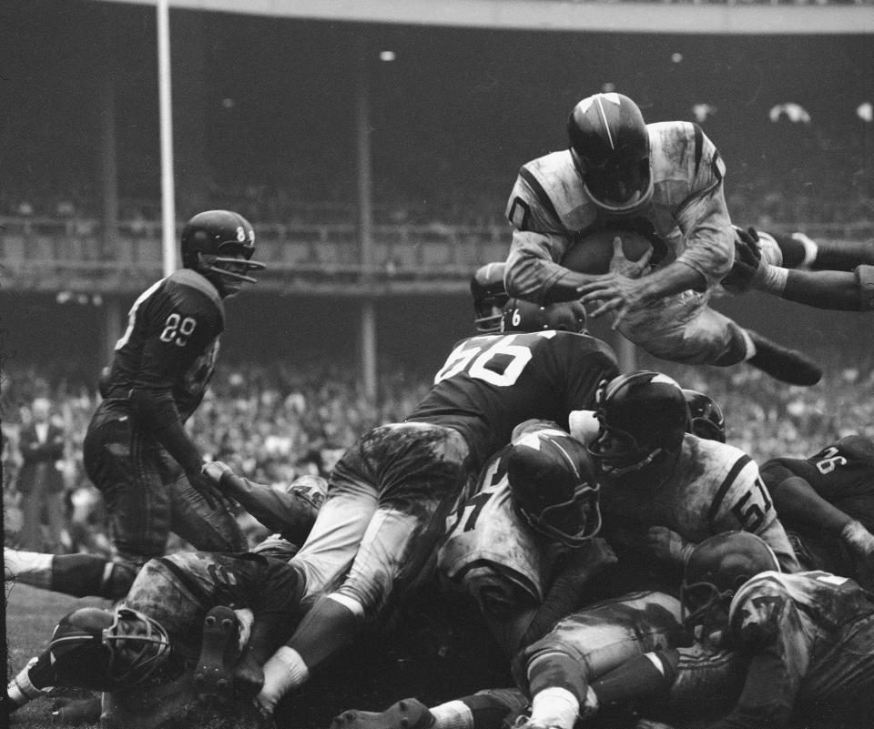 American professional football player Johnny Olszewski of the Washington Redskins leaps with the ball over a pile of New York defensemen and his own teammates to make a touchdown, Yankee Stadium, New York, 1960. The game ended in a tie, 24 to 24. (Photo by Robert Riger/Getty Images)