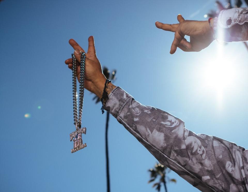 Suga Free holds up jewelry under the sunny L.A. sky.