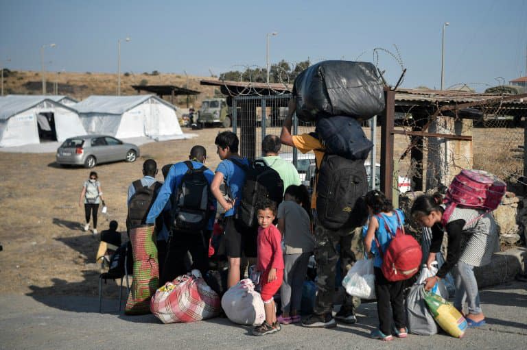 Des migrants attendent pour être dirigés vers  un nouveau campement de réfugiés après l'incendie du camp de Moria, sur l'ile de Lesbos, le 12 septembre 2020 - LOUISA GOULIAMAKI © 2019 AFP