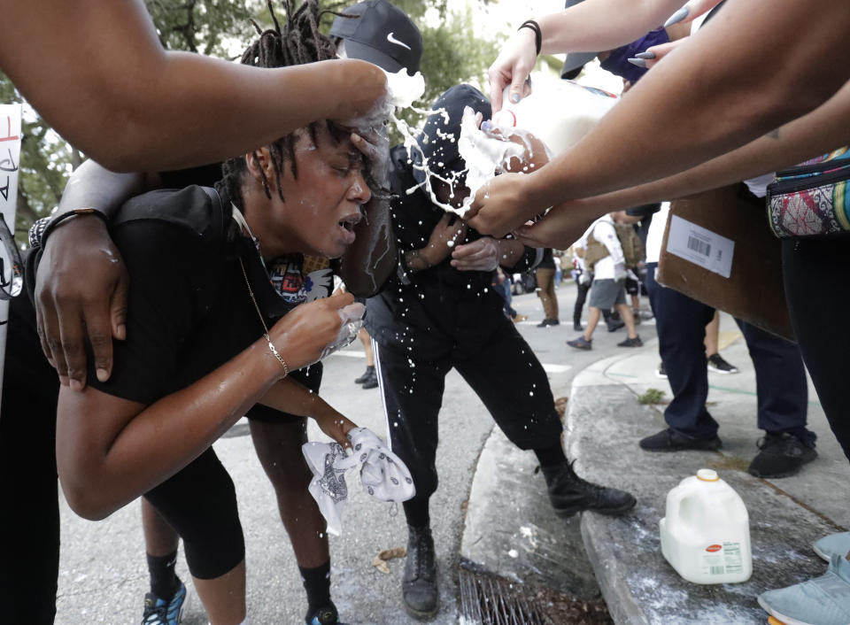 Protesters pour milk in the eyes of a woman affected by teargas during a rally at the Miami Police Department on Saturday, May 30, 2020, to protest the death of George Floyd, a black man who was killed in police custody in Minneapolis on May 25. (AP Photo/Wilfredo Lee)