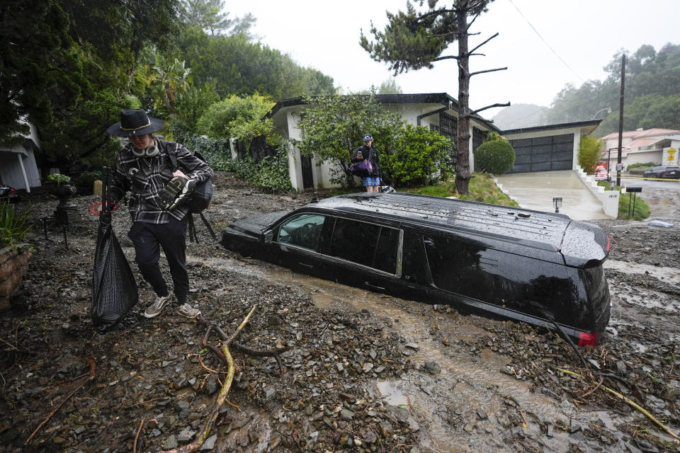 Residents evacuate past damaged vehicles after storms caused a mudslide, Monday, Feb. 5, 2024, in the Beverly Crest area of Los Angeles. / Credit: Marcio Jose Sanchez / AP