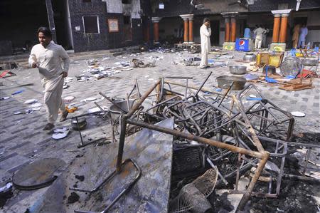 Members of the Hindu community walk inside a temple that was attacked on Saturday night, in Larkana, southern Pakistan's Sindh province, March 16, 2014. REUTERS/Faheem Soormro