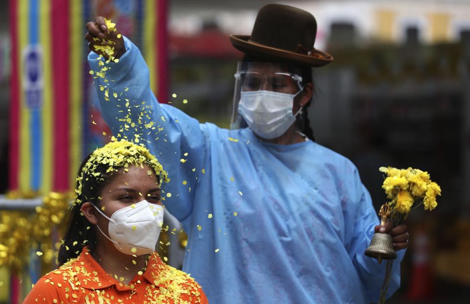 Brigite Garcés se queda quieta mientras una chamana rocía confeti sobre su cabeza durante un ritual de limpieza por alrededor de 10 dólares en el "Mercado de Deseos", que se instala durante una semana en Lima, Perú, el lunes 28 de diciembre de 2020. En medio de la pandemia de COVID-19 de este año, la gente desea tener buena salud y trabajo en 2021, ya que muchos se han quedado sin ninguno de ellos. Garcés dijo que desea tener buena salud primero, trabajar en segundo lugar y luego amar. (AP Foto/Martin Mejia)