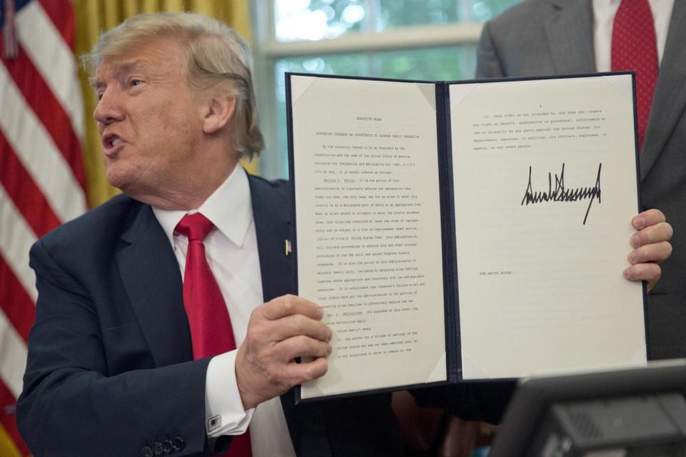 Donald Trump holds up the executive order he signed to end family separations at the border (AP)