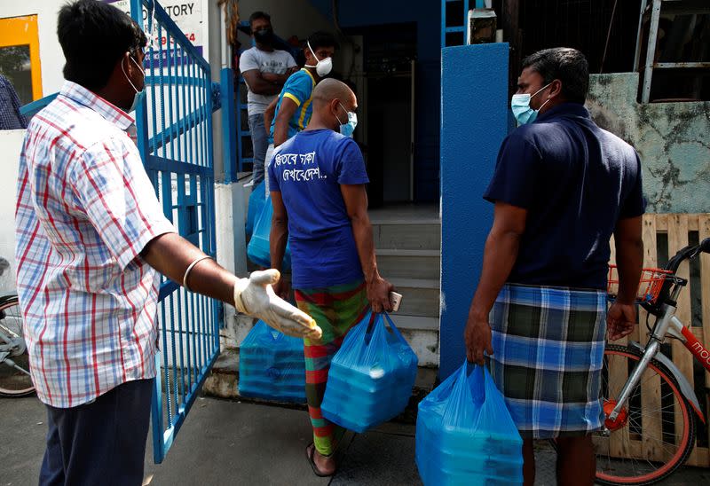 Migrant workers living in a factory-converted dormitory collect the food delivered by non-governmental organization Alliance of Guest Workers Outreach (AGWO) during the coronavirus disease (COVID-19) outbreak in Singapore