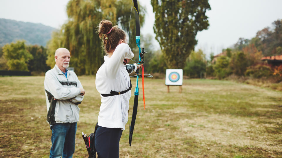 Teenage girl on archery training with her father as a coach.