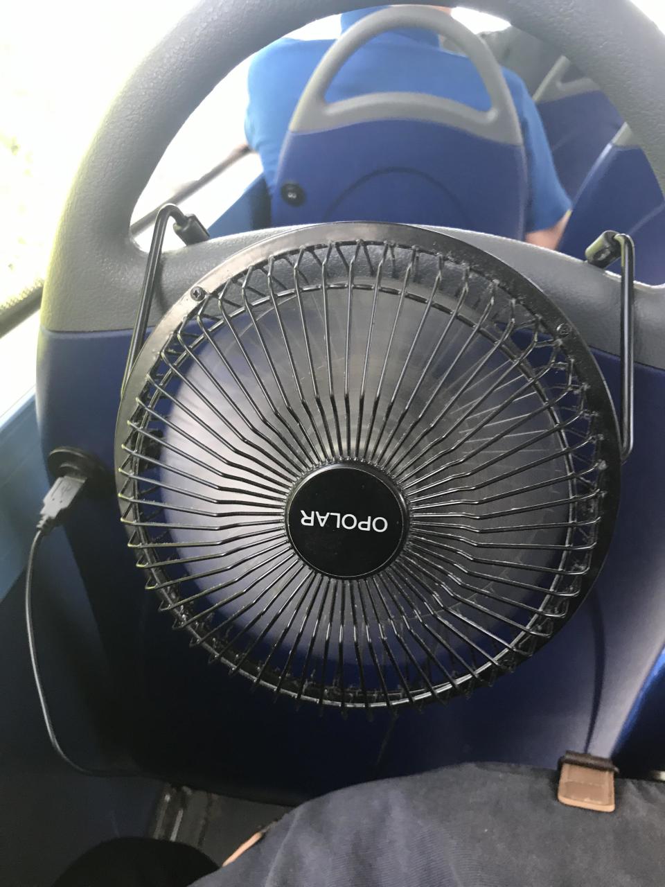 a usb fan hanging on the seat of a bus