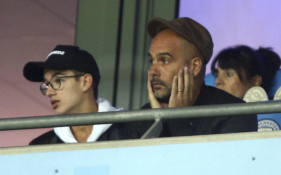 Manchester City's coach Pep Guardiola, right, reacts as he sits in the stands during the Champions League Group F soccer match between Manchester City and Lyon at the Etihad stadium in Manchester, England, Wednesday, Sept. 19, 2018. (AP Photo/Dave Thompson)