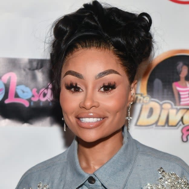 Blac Chyna at an event wearing a denim shirt with sparkly embellishments. Her hair is styled up