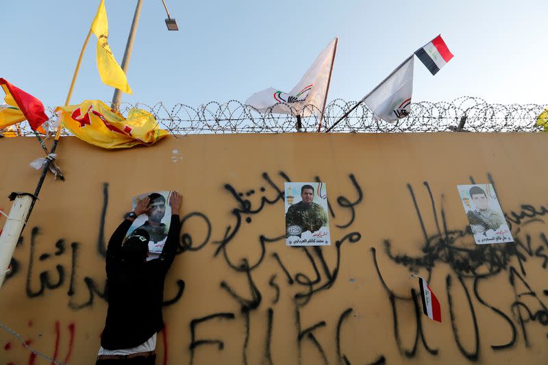 A protester puts pictures of fighters who were killed by U.S. air strikes during a protest to condemn air strikes on bases belonging to Hashd al-Shaabi (paramilitary forces), in Baghdad