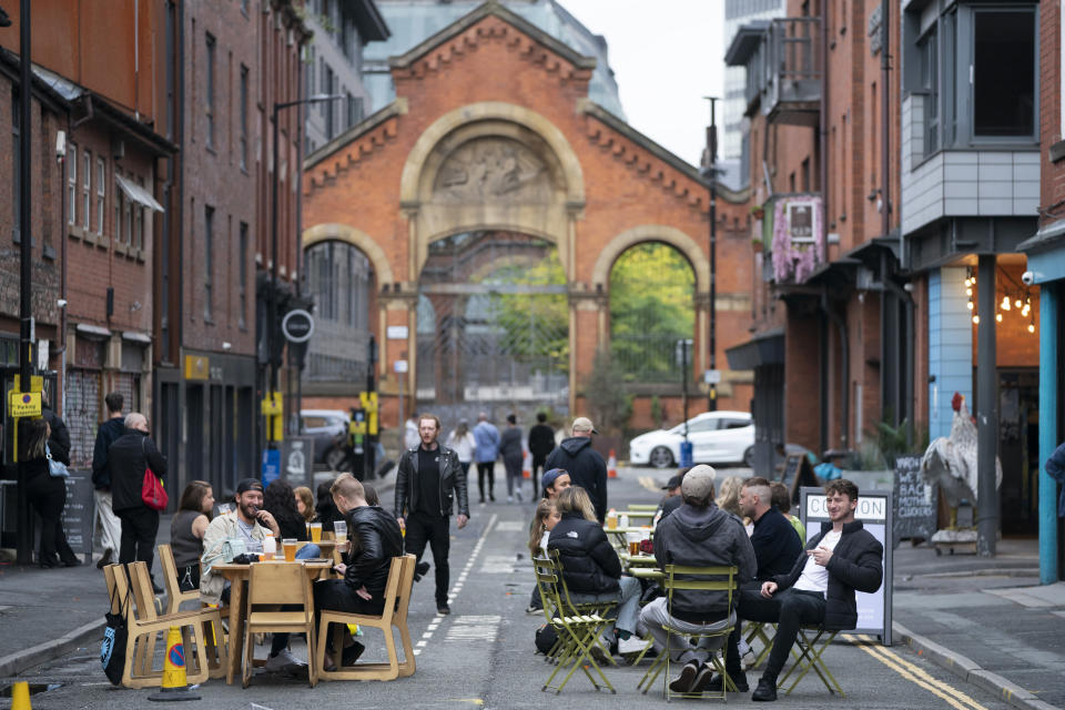 Members of the public are seen at a bar in Manchester's Northern Quarter, England, Saturday July 4, 2020. England is embarking on perhaps its biggest lockdown easing yet as pubs and restaurants have the right to reopen for the first time in more than three months. In addition to the reopening of much of the hospitality sector, couples can tie the knot once again, while many of those who have had enough of their lockdown hair can finally get a trim. (AP Photo/Jon Super)