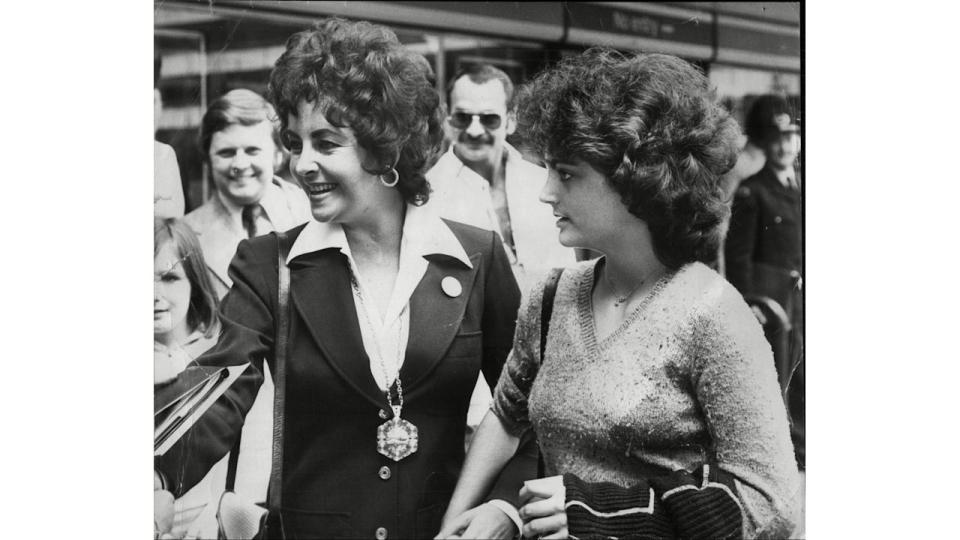 Black-and-white photo of Elizabeth Taylor walking with daughter Liza Todd