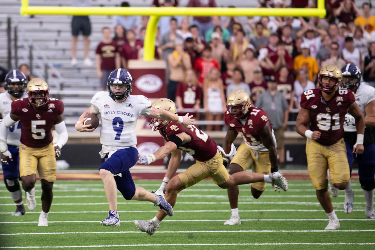 After play resumed Holy Cross’s Mathew Sluka evades a seas of Boston College defenders for a first down on Saturday September 9, 2023 at Alumni Stadium in Newton.