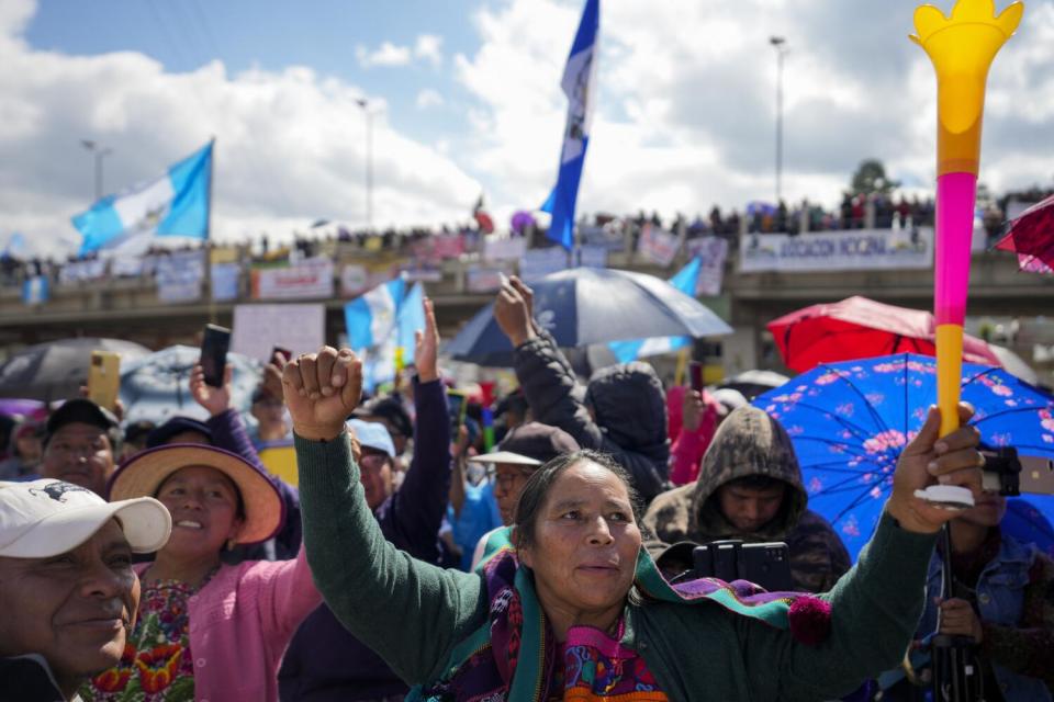 Protestors raising colorful parasols and flags as others hang banners from an overpass