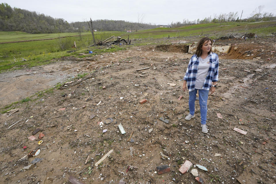 CORRECTS STATE TO KENTUCKY INSTEAD OF TENNESSEE - Chris Bullock stands where her former home stood April 21, 2022, in Dawson Springs, Ky. Bullock, her husband, a son, and family dog survived a massive tornado as it destroyed the home by huddling in a corner of the basement Dec. 10. Four months after the tornado upended her family's lives, Bullock and hundreds of other Kentuckians are arduously reconstructing their pre-storm existence. (AP Photo/Mark Humphrey)