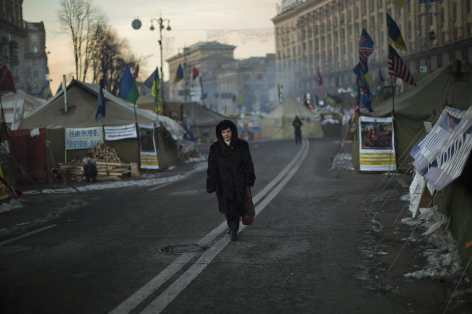 A woman walks past tents set up in the middle of the street by opposition supporters near to Kiev's Independence Square, the epicenter of the country's current unrest, Ukraine, Wednesday, Feb. 5, 2014. The mayor of a western city warned that his police would fight any troops sent in by the president. The governor of an eastern region posted an image of an opposition lawmaker beaten bloody, saying he couldn't contain his laughter. Two months into Ukraine's anti-government protests, the two sides are only moving further apart. (AP Photo/Emilio Morenatti)