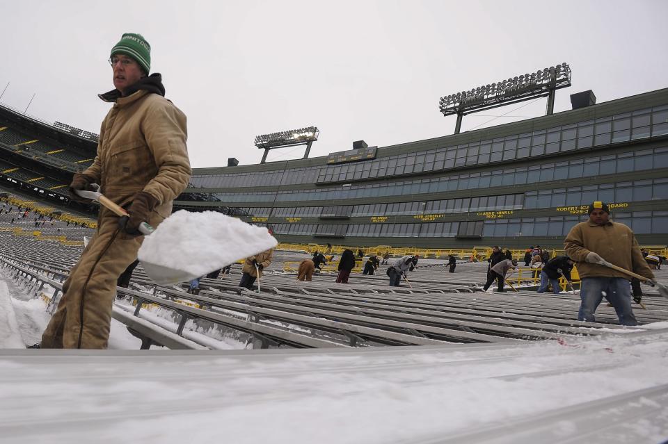 A man shovels snow from the bleachers at Lambeau Field in Green Bay, Wisconsin, the home field of the Green Bay Packers of the National Football League (NFL), December 21, 2013. In winter months, the team calls on the help of hundreds of citizens, who also get paid a $10 per-hour wage, to shovel snow and ice from the seating area ahead of games, local media reported. The Packers will host the Pittsburgh Steelers on Sunday, December 22. REUTERS/Mark Kauzlarich (UNITED STATES - Tags: ENVIRONMENT SPORT FOOTBALL)