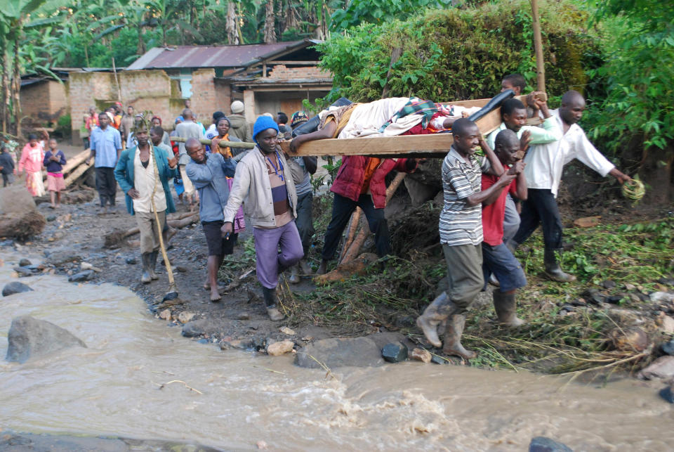 Residence carry an injured person in Bududa District, Uganda, Friday, Oct. 12, 2018. At least 30 people died in mudslides triggered by torrential rains in a mountainous area of eastern Uganda that is prone to such disasters, a Red Cross official said Friday. More victims were likely to be discovered when rescue teams access all the affected areas in the foothills of Mount Elgon, said Red Cross spokeswoman Irene Nakasiita. (AP Photo/ Ronald Kabuubi)