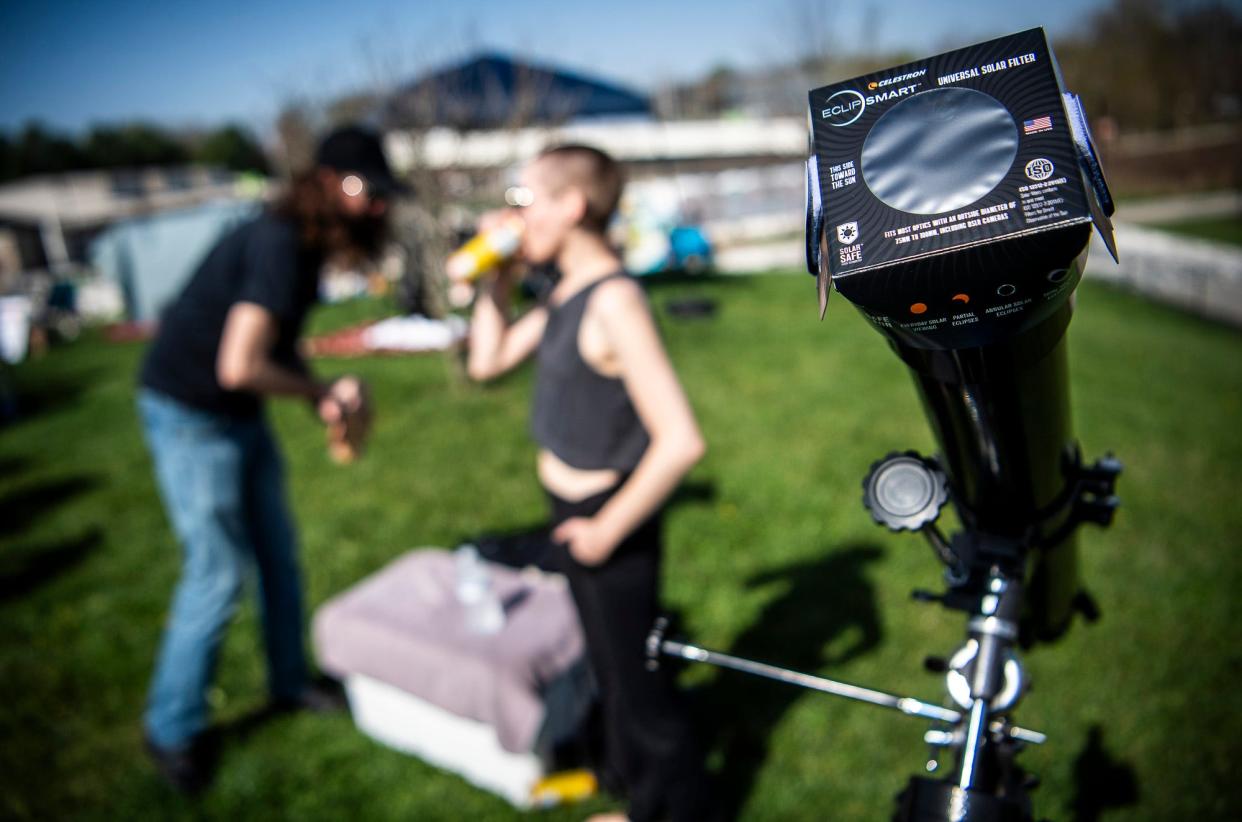 Landon Roberson, left, and Hann Burleson, right, enjoy refreshments after getting their telescope and sun filter set up at Switchyard Park for the eclipse day on April 8, 2024.