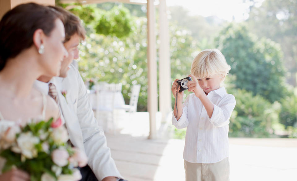 Boy taking photo of bride and groom