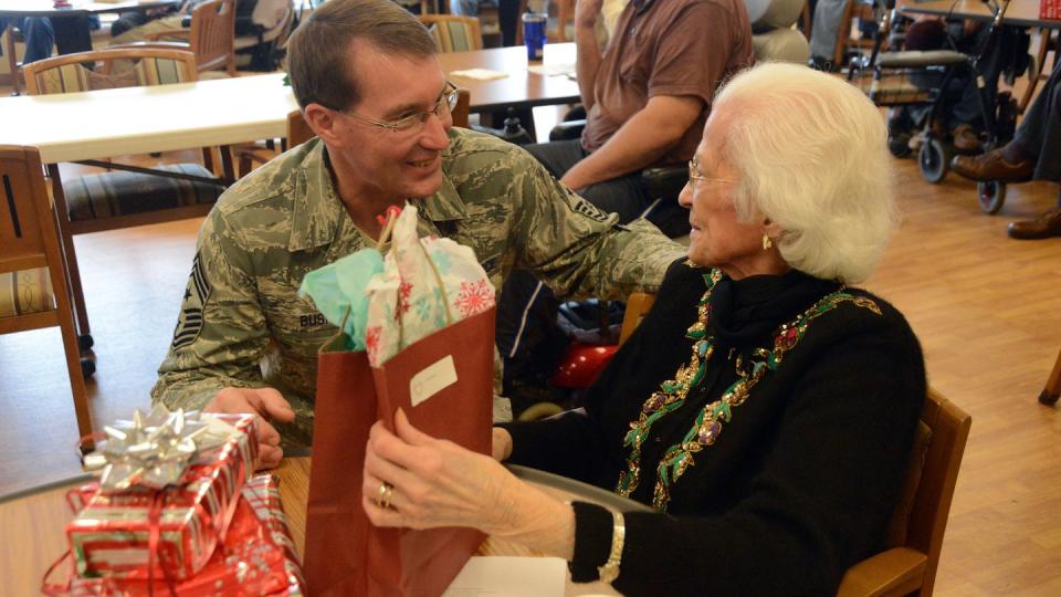 Air Force Chief Master Sgt. Ben Bush, the North Dakota National Guard State Command Chief, left, gives a gift and visits with a resident at the North Dakota Veterans Home in 2014, in Lisbon, North Dakota. (Senior Master Sgt. David H. Lipp/North Dakota National Guard)