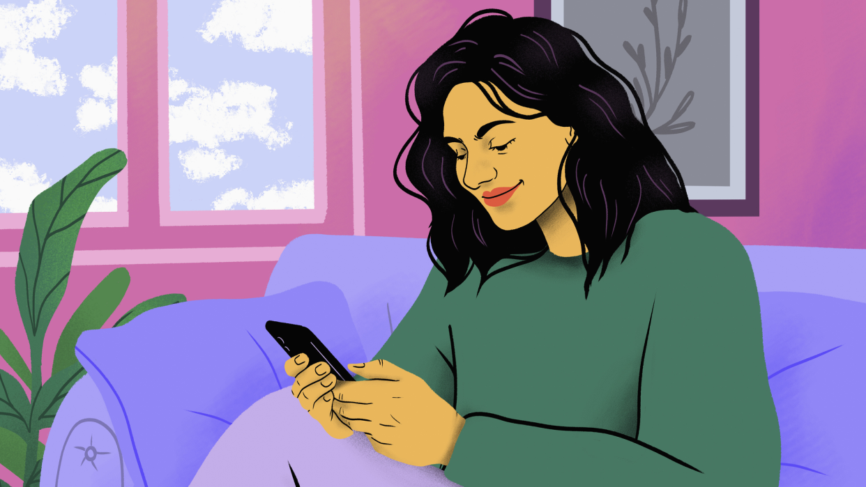  Young woman using a mobile phone while sitting on a purple couch. 