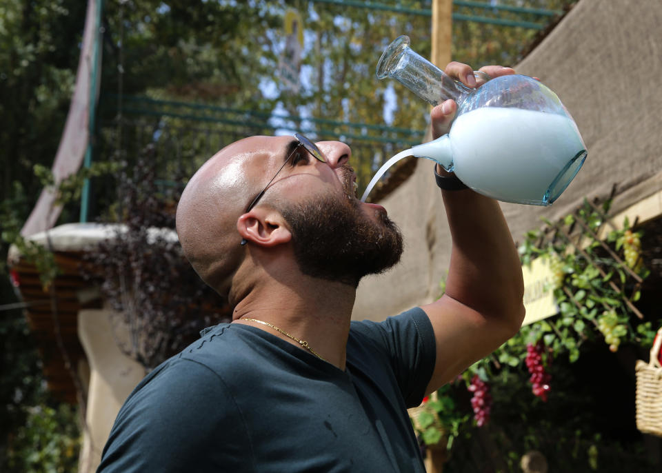 In this Saturday Sept. 8, 2018 photo, a Lebanese man drinks arak from a traditional glass pitcher during a festival that celebrates Lebanon's national alcoholic drink, in the town of Taanayel, east Lebanon. The anise-tinged arak, is surrounded by ritual -- from its distilling down to the moment when it’s mixed, turning milky white in water, and drunk over long, lingering meals. (AP Photo/Hussein Malla)