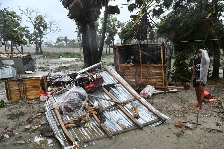 La gente se encuentra junto a una tienda dañada tras la llegada del ciclón Remal cerca de una playa en Kuakata el 27 de mayo de 2024.