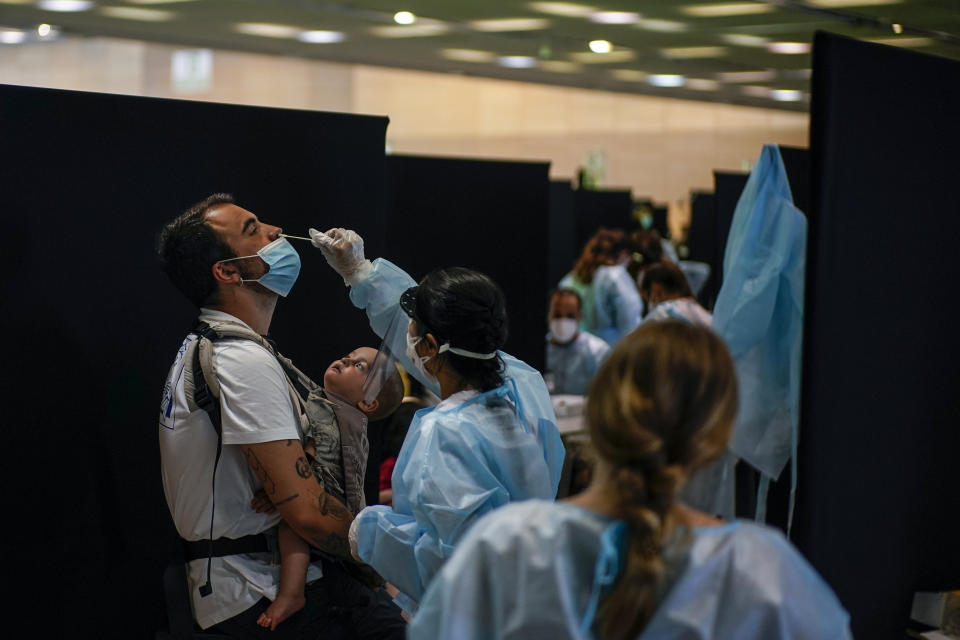 A health worker takes a swab sample collection for a COVID-19 Antigen test as a baby watches, ahead of the Cruilla music festival in Barcelona, Spain, Friday, July 9, 2021. (AP Photo/Joan Mateu)