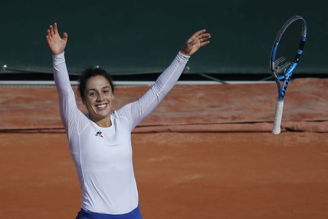 Martina Trevisan throws her racket in the air in celebration after upsetting Kiki Bertens