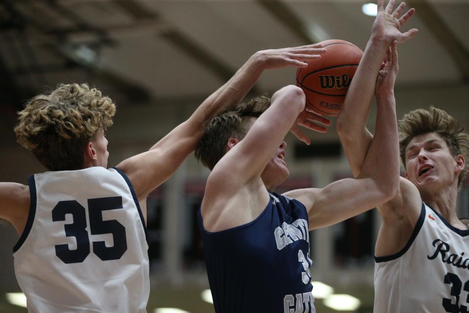 Central Catholic forward Albert Schwartz (center) attacks the basket and is defended by Harrison guard Kasen Newton (left) and forward Jeffrey Williams (right) during the IU Health Hoops Classic on Tuesday, Nov. 28, 2023.