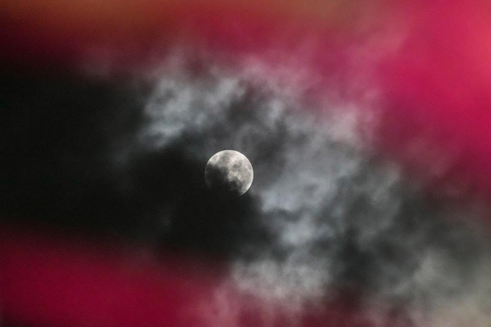 A penumbral lunar eclipse is seen through clouds during the early hours of Saturday in Srinagar, Indian controlled Kashmir, 6 May, 2023 (The Associated Press)