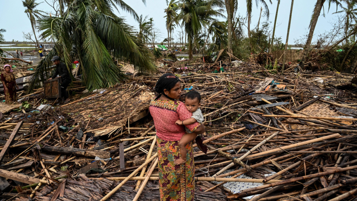  A woman carries her infant child as she looks over destruction wrought by Cyclone Mocha in Myanmar. 