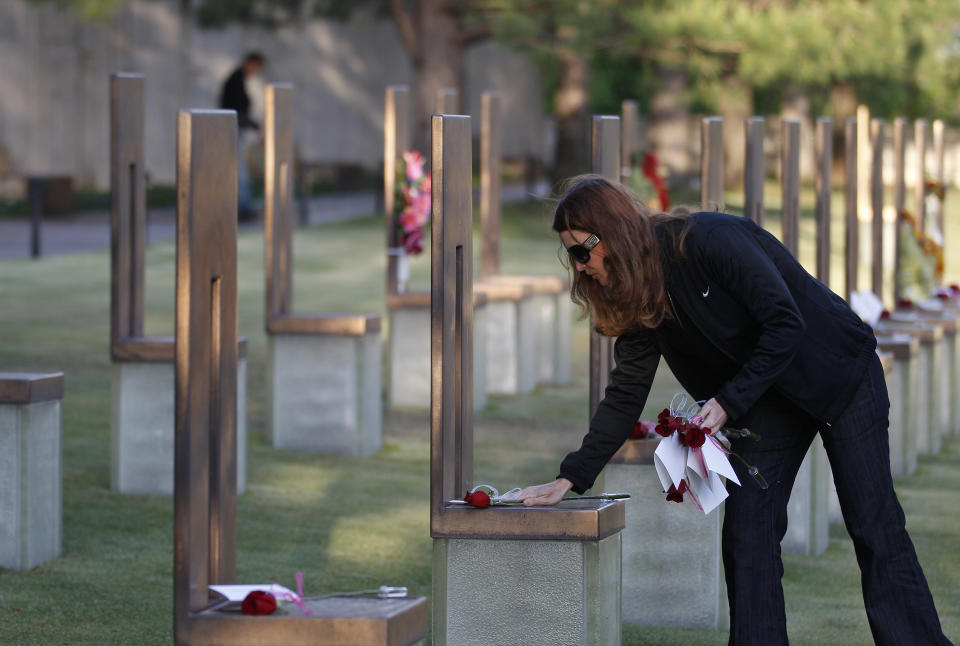 FILE - This April 19, 2012 file photo shows a woman placing flowers on the chairs of bombing victims who worked for HUD, in the Field of Chairs at the Oklahoma City National Memorial & Museum before the start of the 17th annual remembrance ceremony in Oklahoma City. The memorial is where visitors can pay tribute to the people who were killed and those who survived the bombing at the Alfred P. Murrah Federal Building on April 19, 1995. While the Memorial Museum has an admission fee, the outdoor memorial, full of symbolism, is free and open year round. (AP Photo/Sue Ogrocki, File)