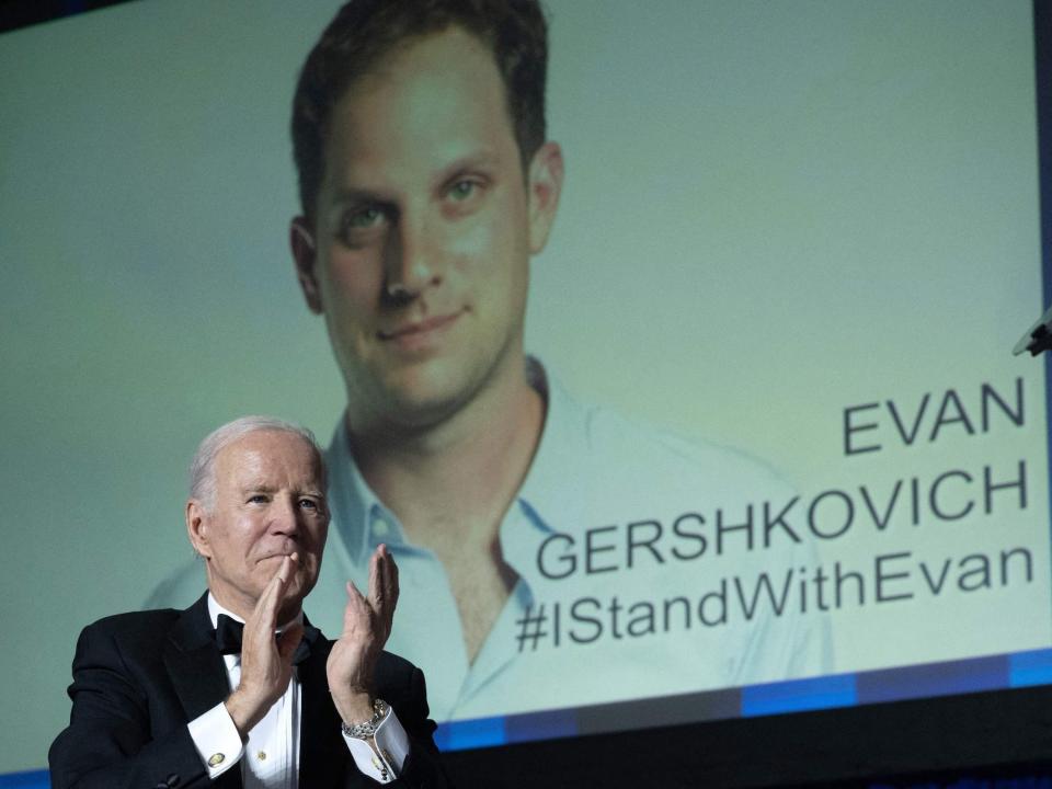 President Joe Biden gestures as an image of US journalist Evan Gershkovich appears onscreen during the White House Correspondents' Association dinner