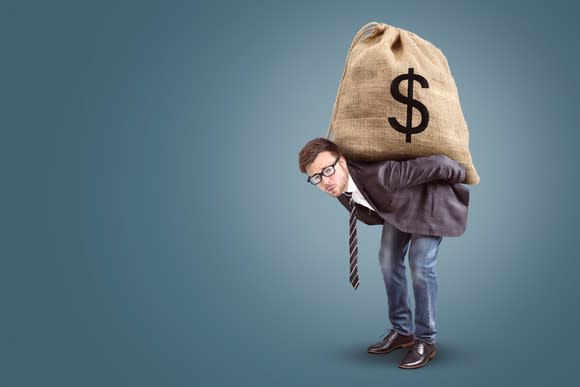A man carrying an oversized sack full of money on his back.