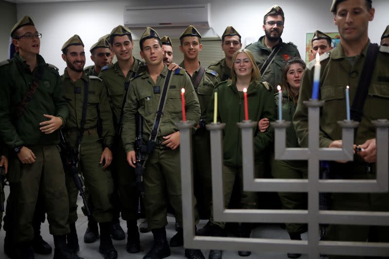 Israeli soldiers from a combat unit gather together to light a hanukkiyah, a candlestick with nine branches that is lit to mark Hanukkah, the 8-day Jewish Festival of Lights, at Urim base in southern Israel