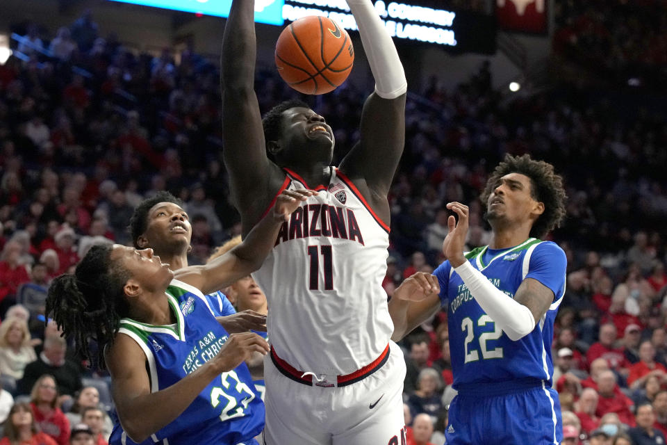 Arizona center Oumar Ballo (11) gets fouled, driving between Texas A&M Corpus Christi guard Ross Williams (23) and guard Simeon Fryer (22) during the second half of an NCAA college basketball game, Tuesday, Dec. 13, 2022, in Tucson, Ariz. Arizona won 99-61. (AP Photo/Rick Scuteri)