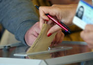 Someone casts a vote at a voting center during the first round of the municipal elections, in Saint Pee sur Nivelle, southwestern France, Sunday March 15, 2020. France is holding nationwide elections Sunday to choose all of its mayors and other local leaders despite a crackdown on public gatherings because of the new virus. For most people, the new coronavirus causes only mild or moderate symptoms. For some it can cause more severe illness. (AP Photo/Bob Edme)