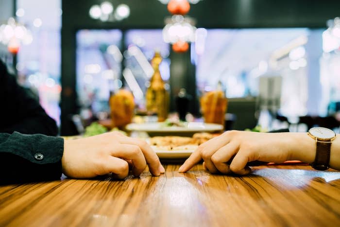 Two people on a date, looking like they want to hold hands, but they don't