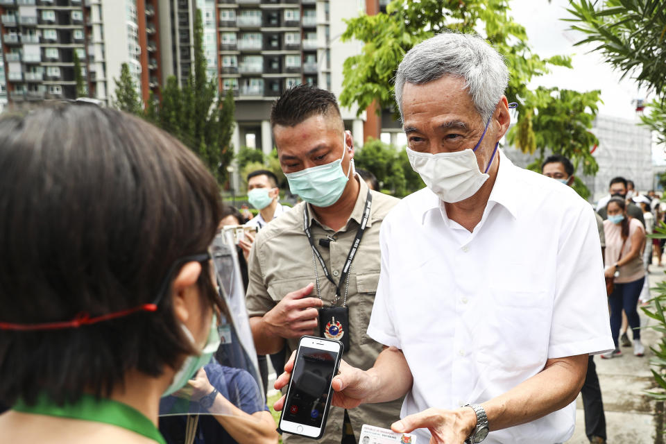 People's Action Party Secretary-General and Singaporean Prime Minister Lee Hsien Loong, right, verifies his identity with a polling official at the Alexandra Primary School polling center in Singapore, Friday, July 10, 2020. Wearing masks and plastic gloves, Singaporeans began voting in a general election that is expected to return Prime Minister Lee's long-governing party to power. (AP Photo)