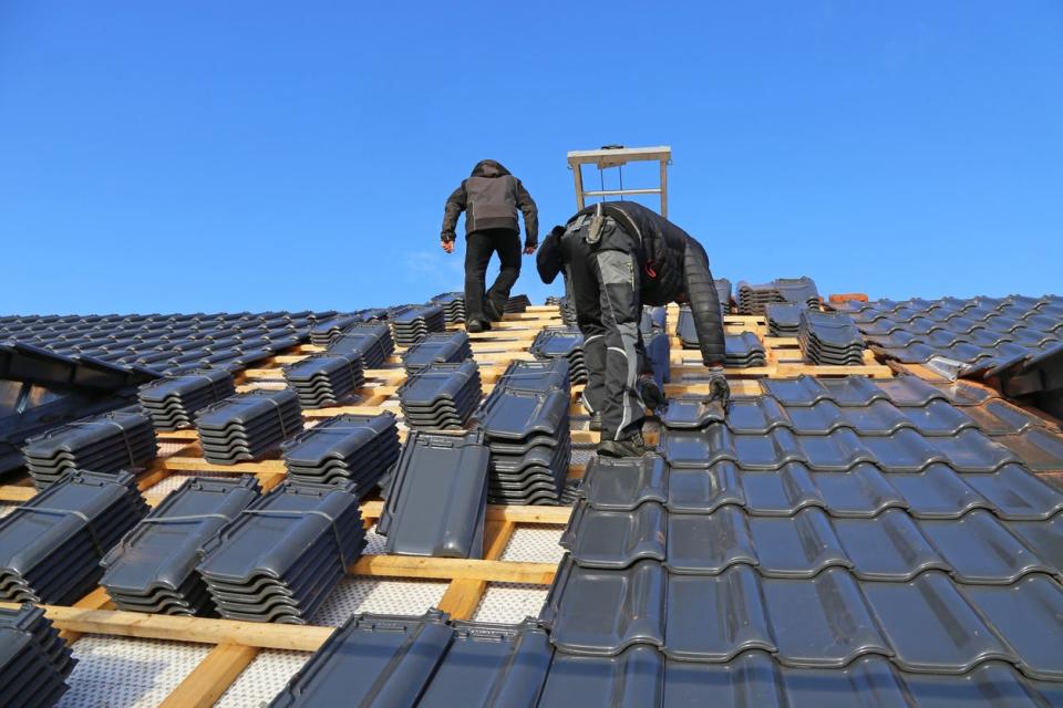 Two roofers install a metal roof.