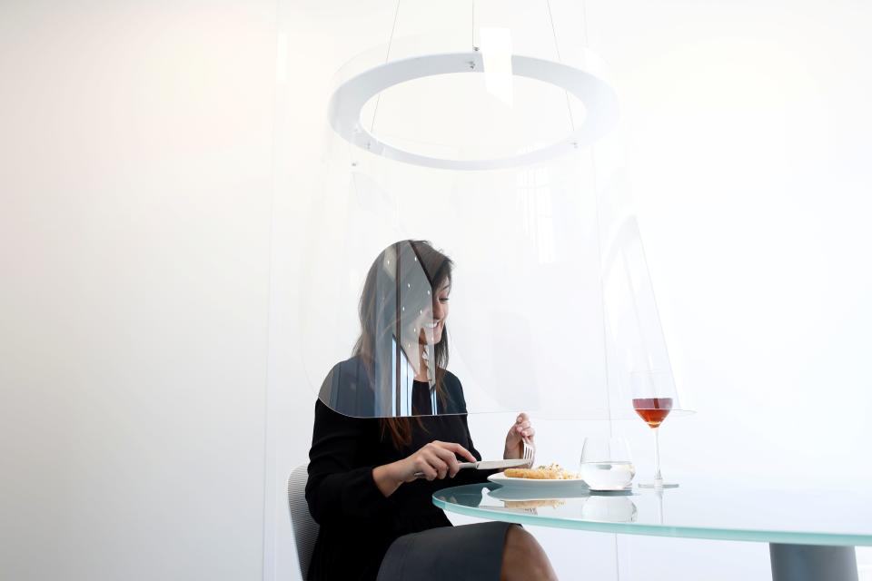 A woman poses under a Plex'Eat prototype plexiglas bubble by designer Christophe Gernigon which surrounds diners to protect them from the novel coronavirus during a presentation in Cormeilles-en-Parisis, near Paris, as restaurants in France prepare to re-open post-lockdown, May 20, 2020.