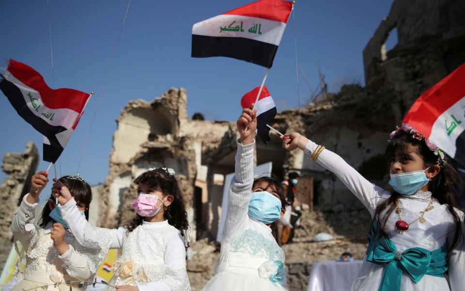 Girls wave national flags as they gather at Church square ahead of Pope Francis' arrival to visit Mosul, Iraq, March 7, 2021. - REUTERS/Yara Nardi