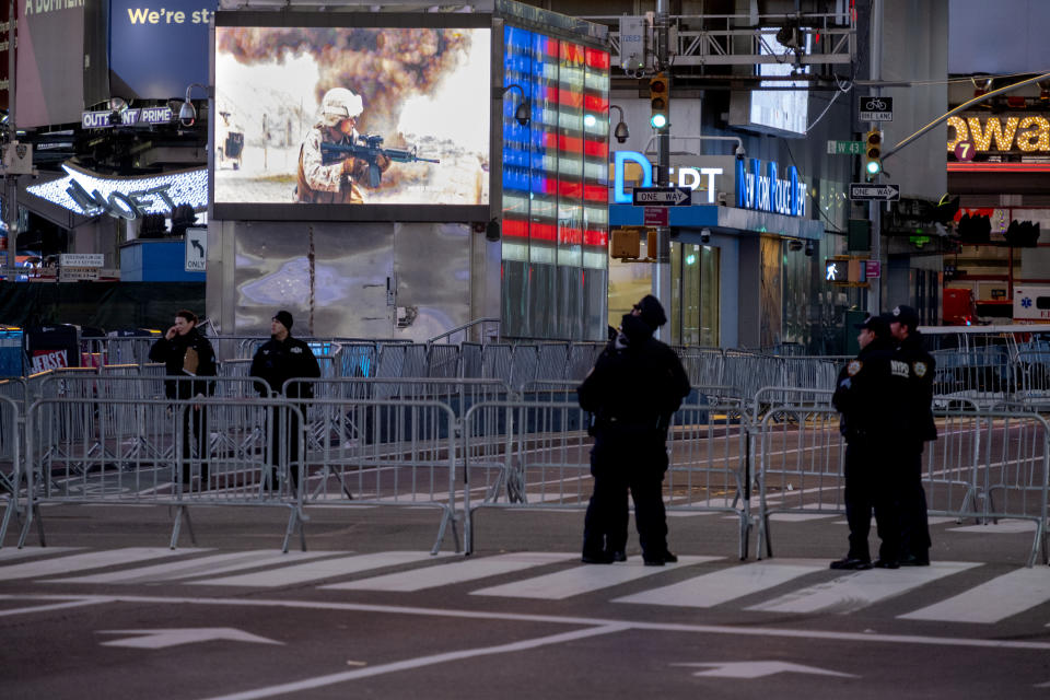 Agentes de policía hacen guardia en una Séptima Avenida casi desierta, en lo que normalmente habría sido un Times Square abarrotado de gente para celebrar la llegada del año nuevo, en Nueva York, el 31 de diciembre de 2020. Las celebraciones de Año Nuevo se redujeron por la pandemia del coronavirus. (AP Foto/Craig Ruttle)