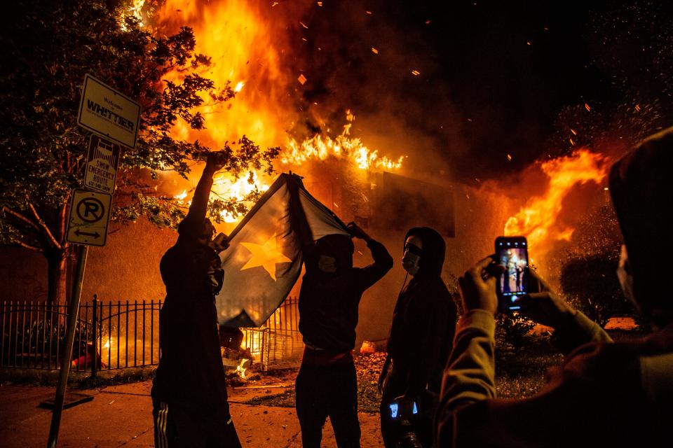Protestors take a photo in front of a burning building on Lake St. in Minneapolis on May 29, 2020.