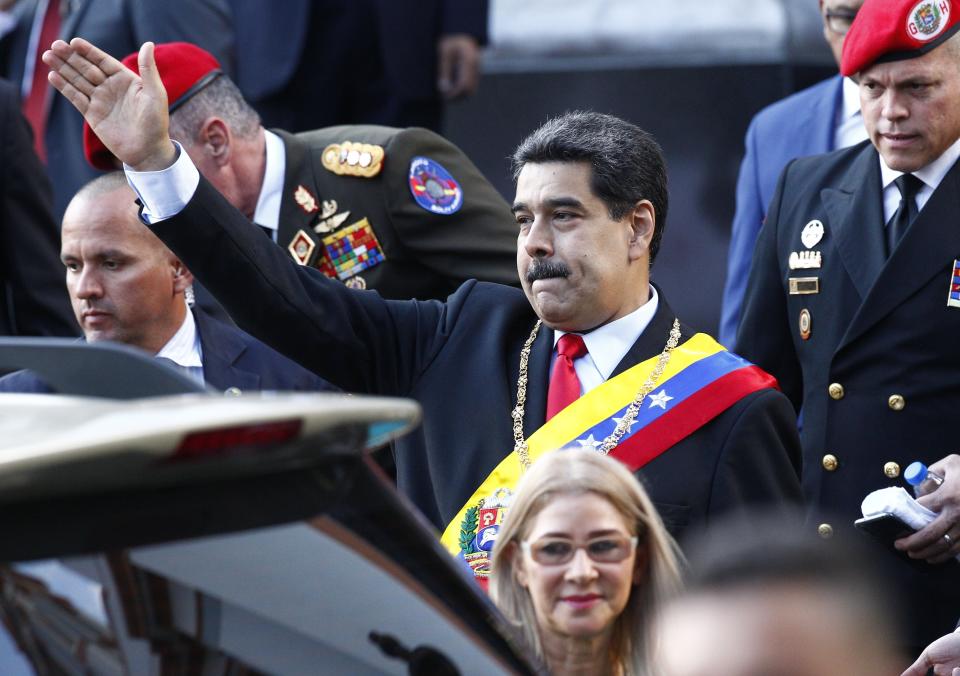 Venezuela's President Nicolas Maduro, accompanied by first lady Cilia Flores, waves to supporters as he leaves the National Pantheon after attending a ceremony to commemorate an 1800's independence battle, in Caracas, Venezuela, Wednesday, Aug. 7, 2019. Sweeping new U.S. sanctions freeze all of the Maduro government's assets in the U.S. and even threaten to punish companies from third countries that keep doing business with his socialist administration. (AP Photo/Leonardo Fernandez)