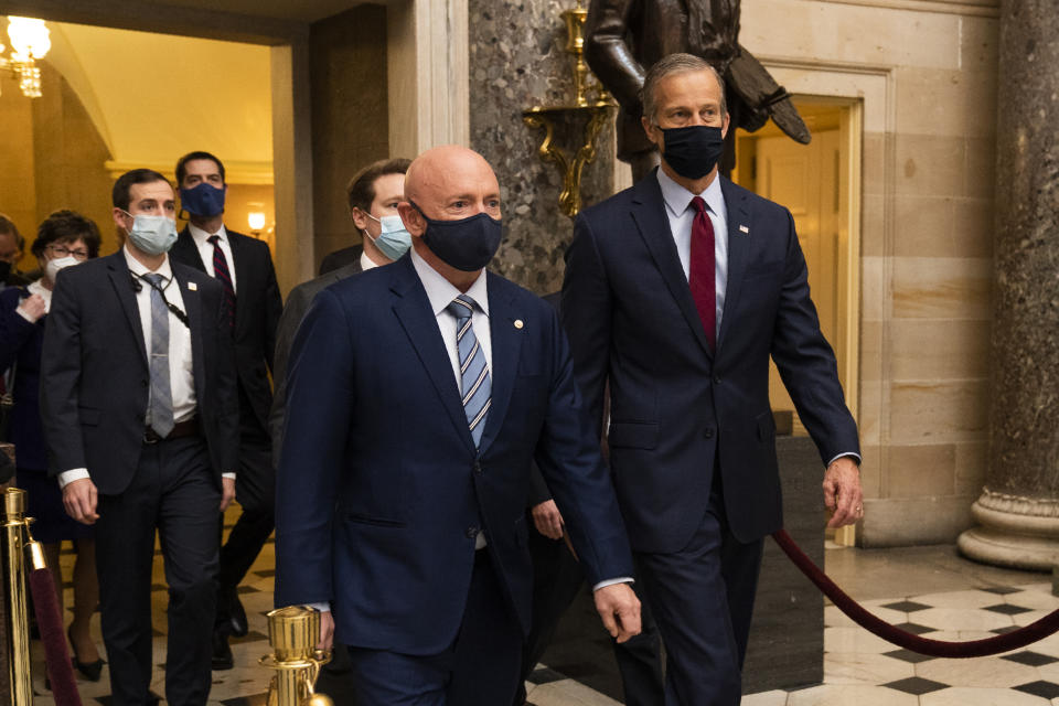 Sen. Mark Kelly, D-Ariz., front left, and and Sen. John Thune, R-S.D. right, walk with fellow senators during a Senate procession carrying boxes holding Electoral College votes through Statuary Hall to the House Chamber for a joint session to confirm the Electoral College votes, Wednesday, Jan. 6, 2021, in Washington. (AP Photo/Manuel Balce Ceneta)